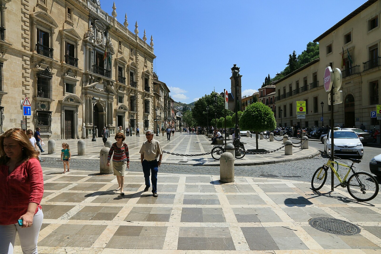 The broad Plaza Nueva in Granada, with a fountain, surrounding buildings, and the Albaicín hill in the background