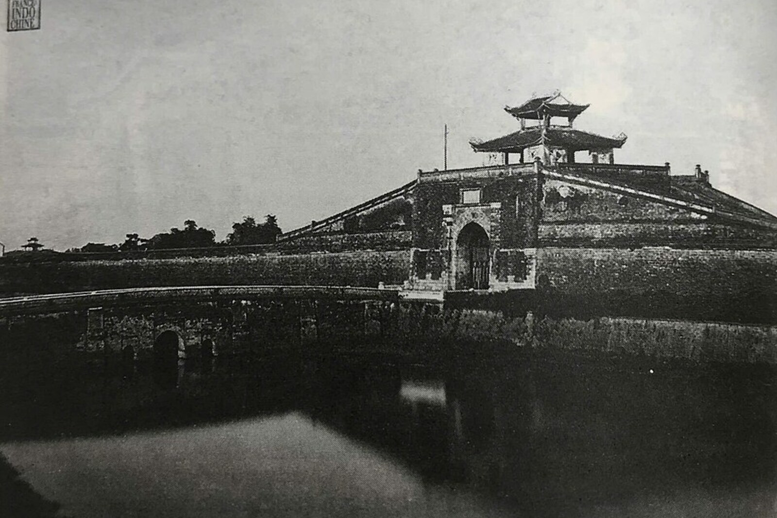 An old stone gate with a wooden pavilion above it and traces of cannon hits.