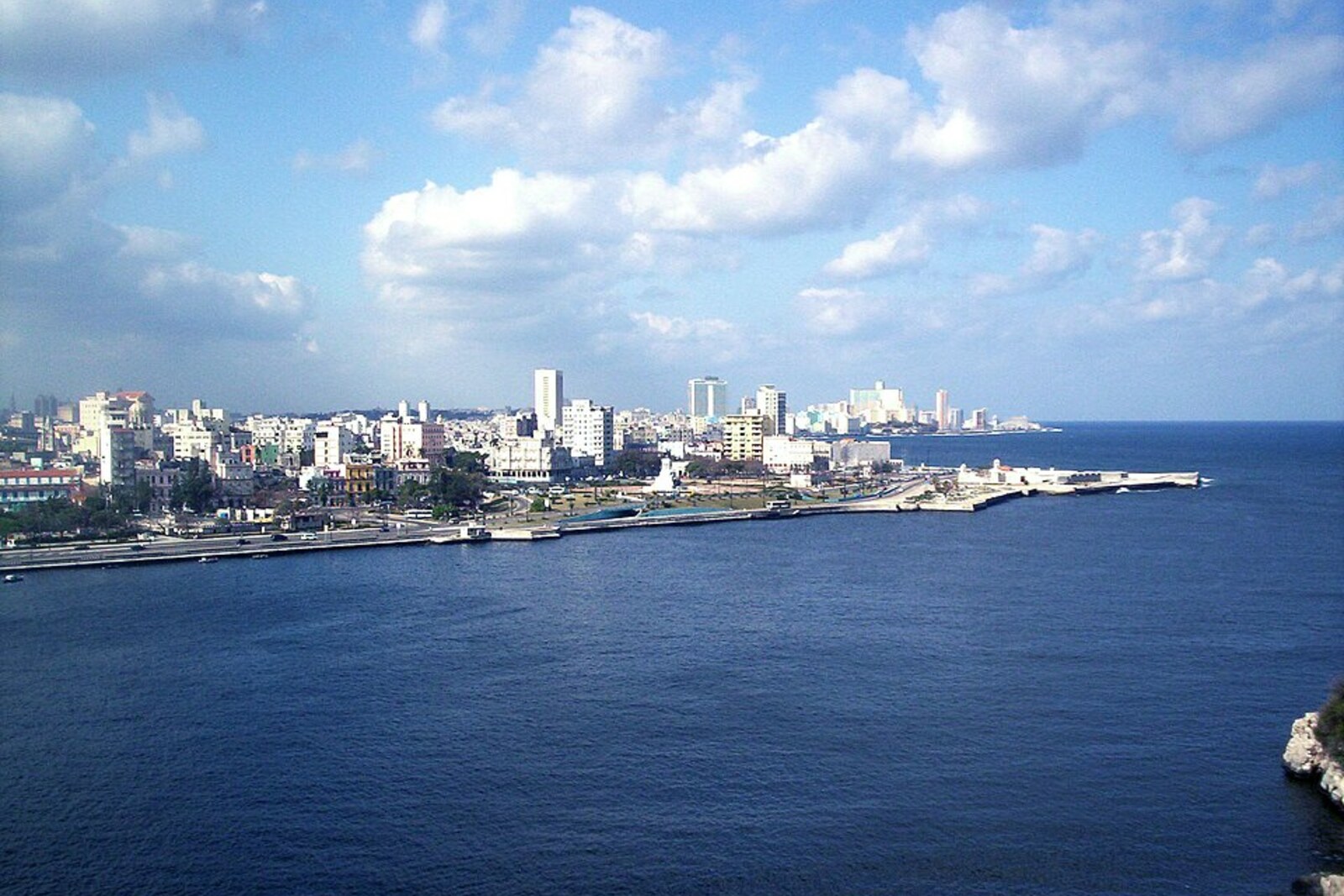 View of the entrance to Havana Bay through a narrow channel, fortress walls on a hill, and calm water