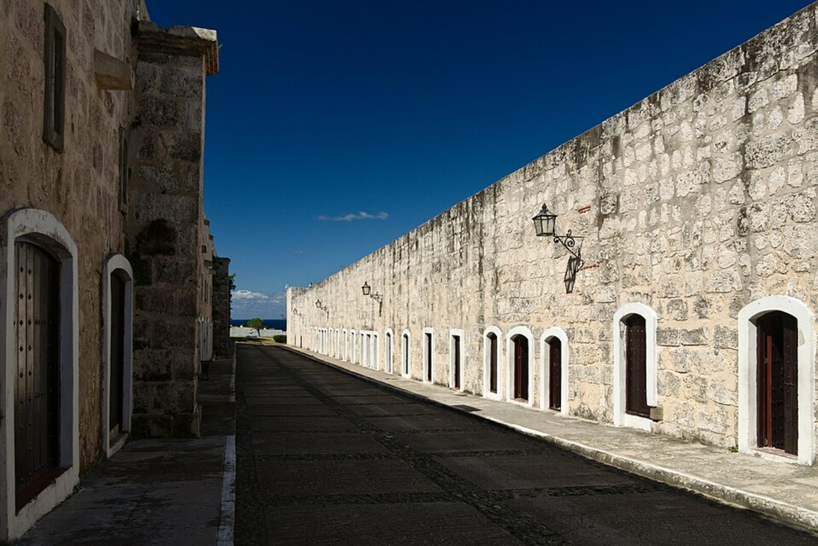 A stone fortress with crenellated walls and a deep moat against a blue sky
