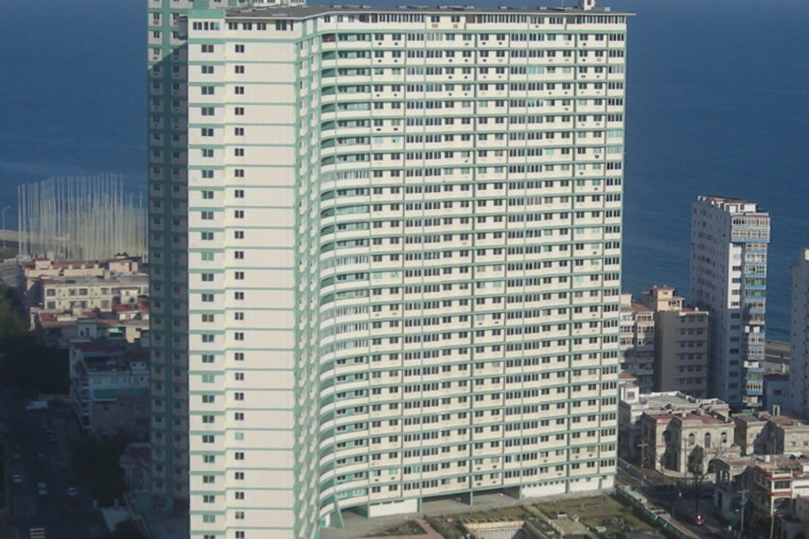 The tall, Y-shaped FOCSA Building rises above the streets of Vedado; trees and passing cars can be seen at its base.