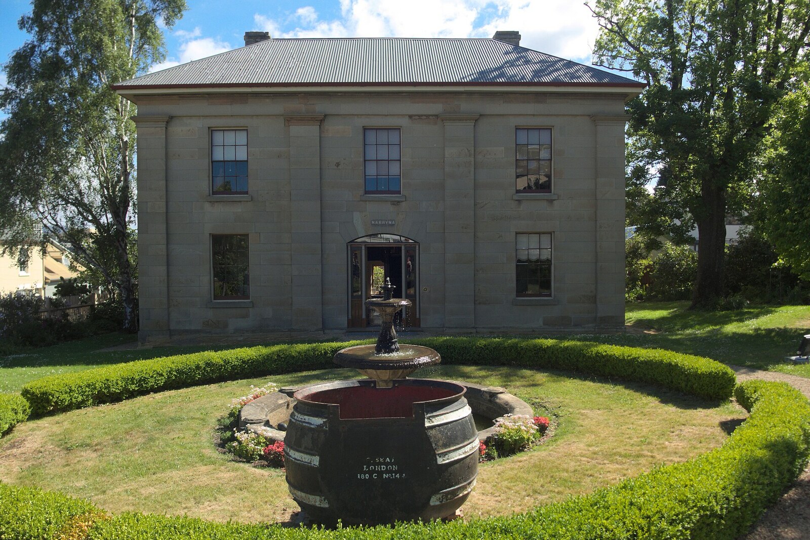 Narryna’s symmetrical two-story facade behind a garden.