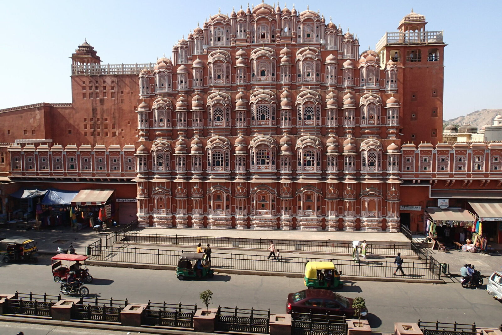 The façade of Hawa Mahal, seen through Badi Chaupar and the flow of city traffic.
