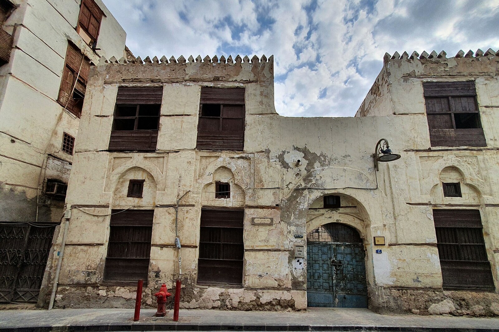 The plastered facade of Ribat Al-Khunji with an arched entrance and a crenellated edge