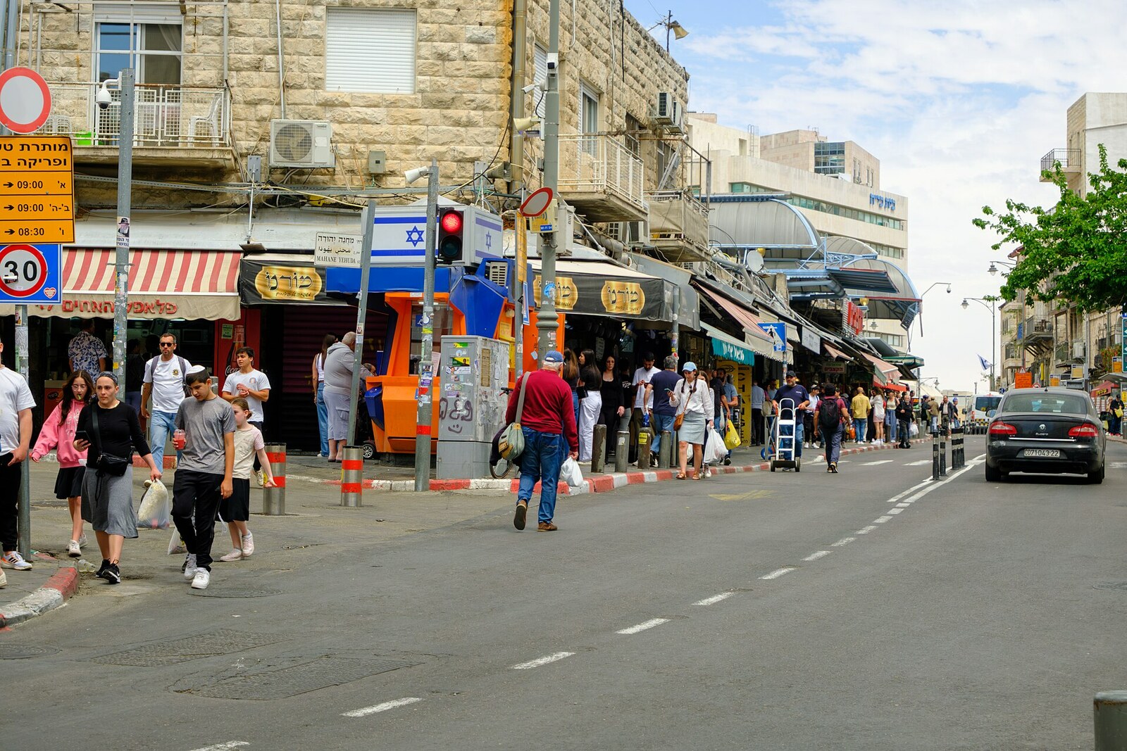 Wide Agrippas Street in Jerusalem, with buses, cars, and shops on both sides