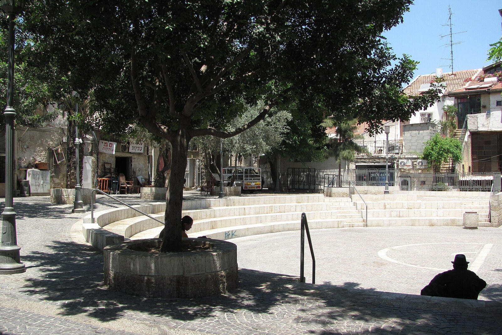 A small stone amphitheater with terraces and shrubs in the central courtyard of Even Yisrael