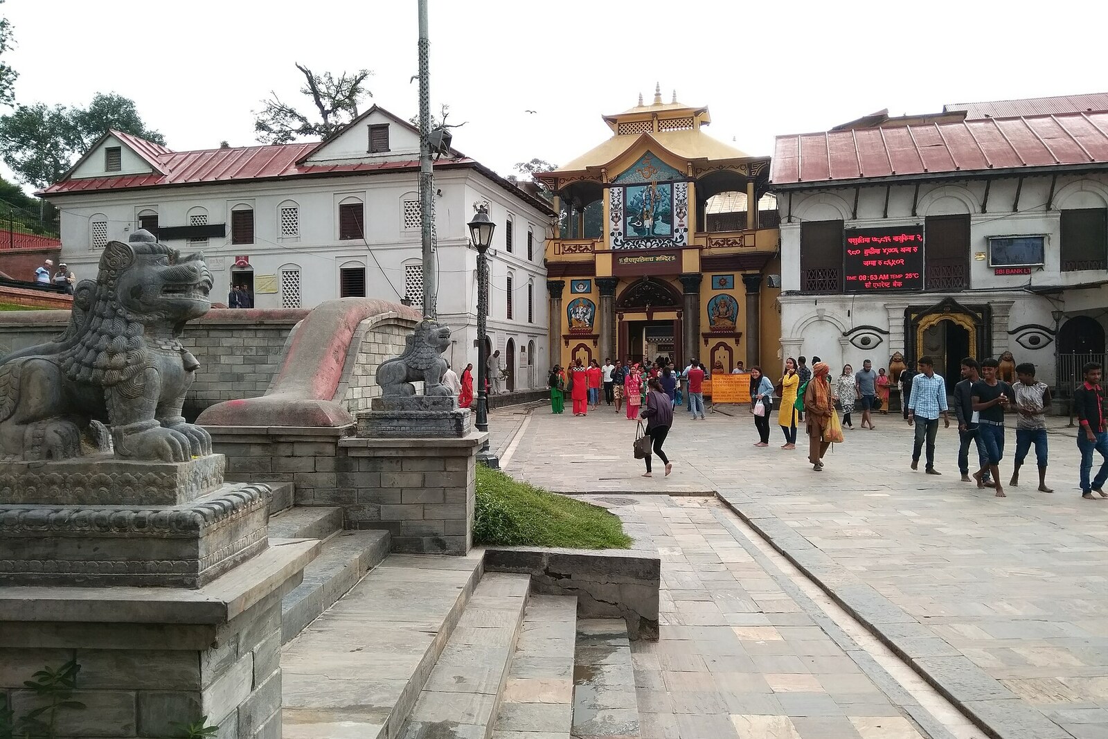 Gilded gates of Pashupatinath Temple with people and monkeys at the entrance