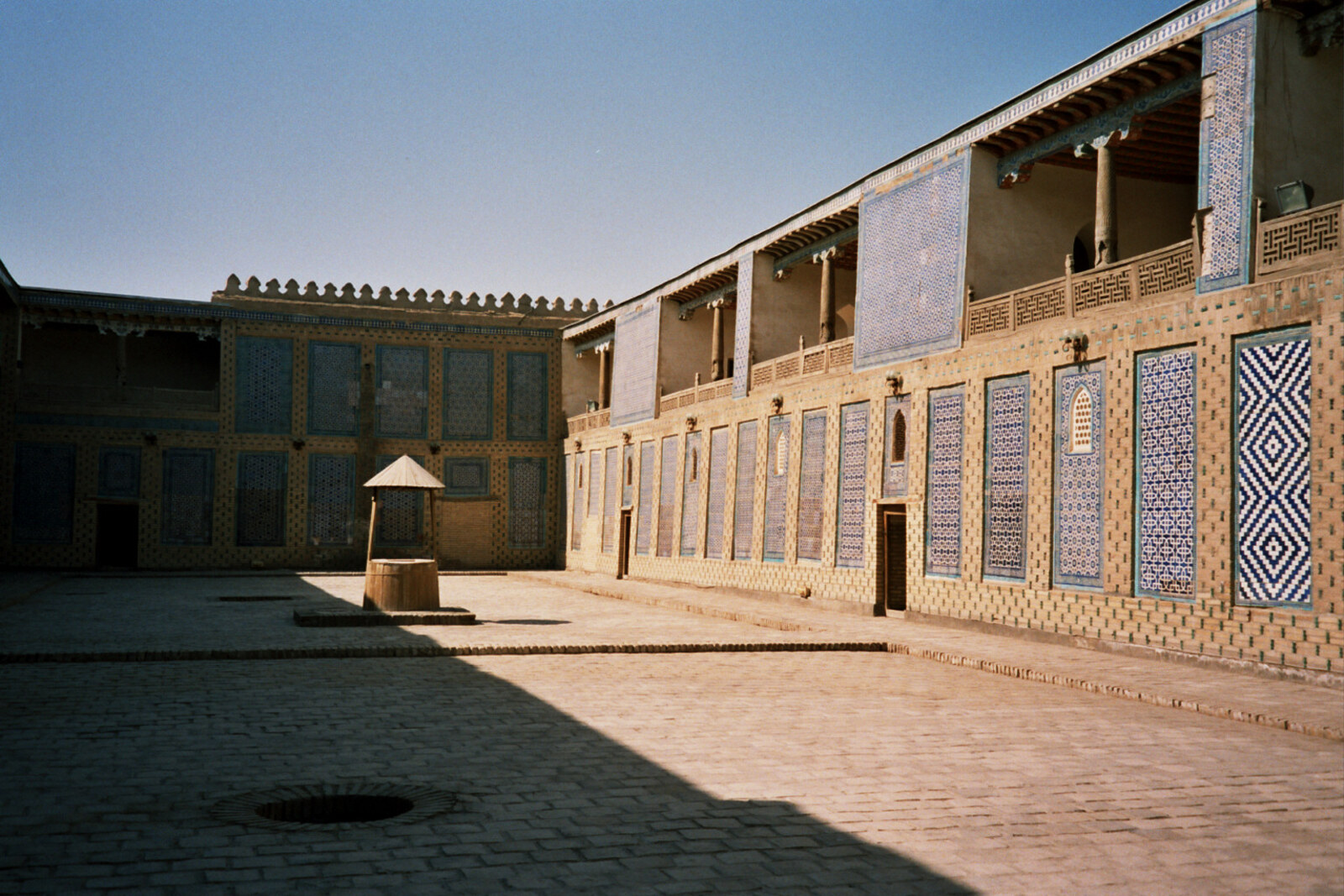 The tiled courtyard of Tash Hauli, with a tall aivan and carved wooden columns.