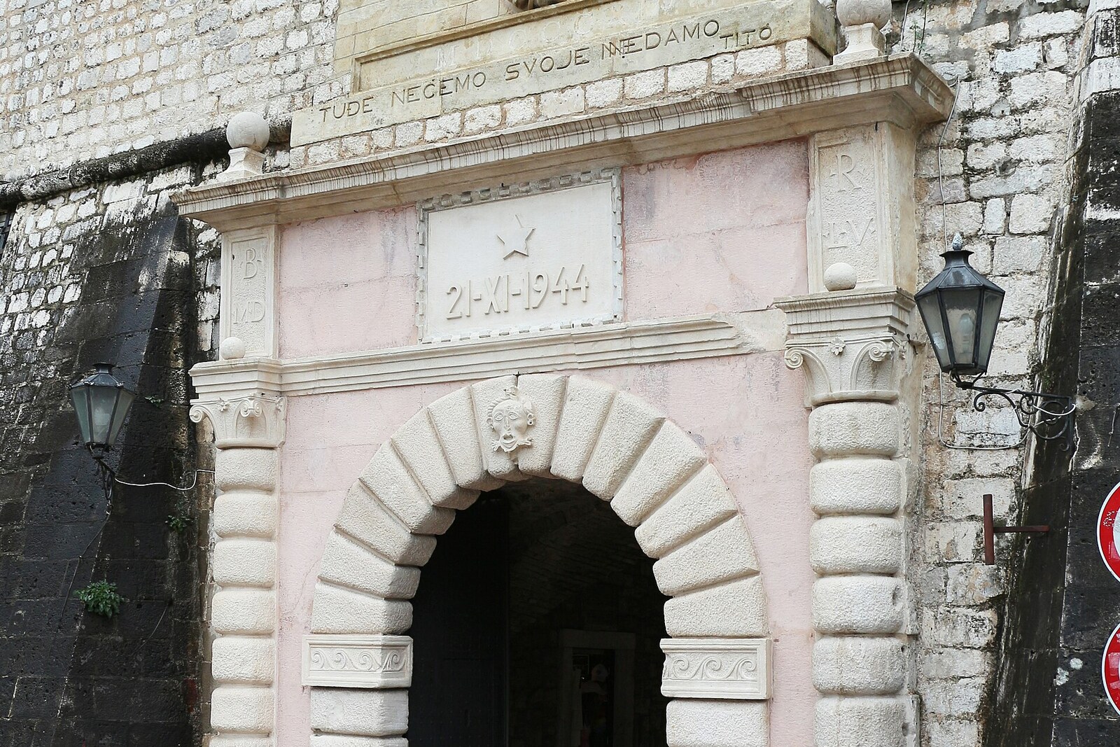 Facade of Kotor's Sea Gate with a coat of arms and commemorative inscription.
