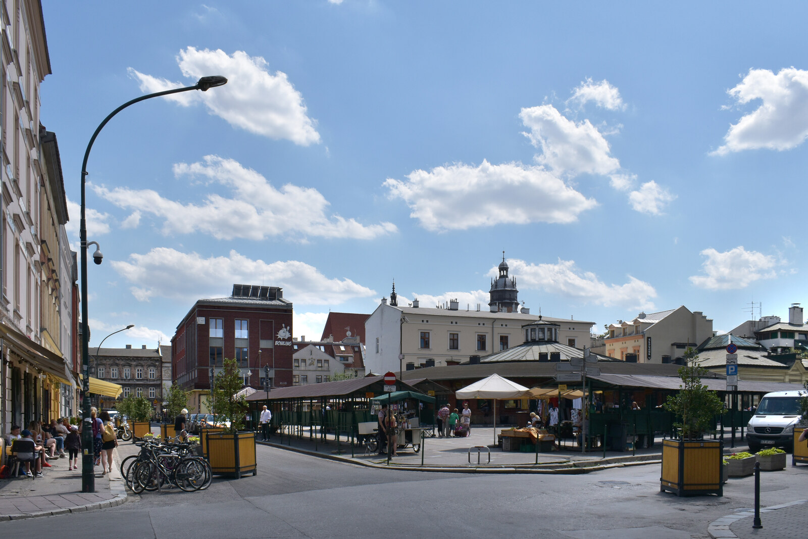 A round brick pavilion in the square, with people and kiosks around it