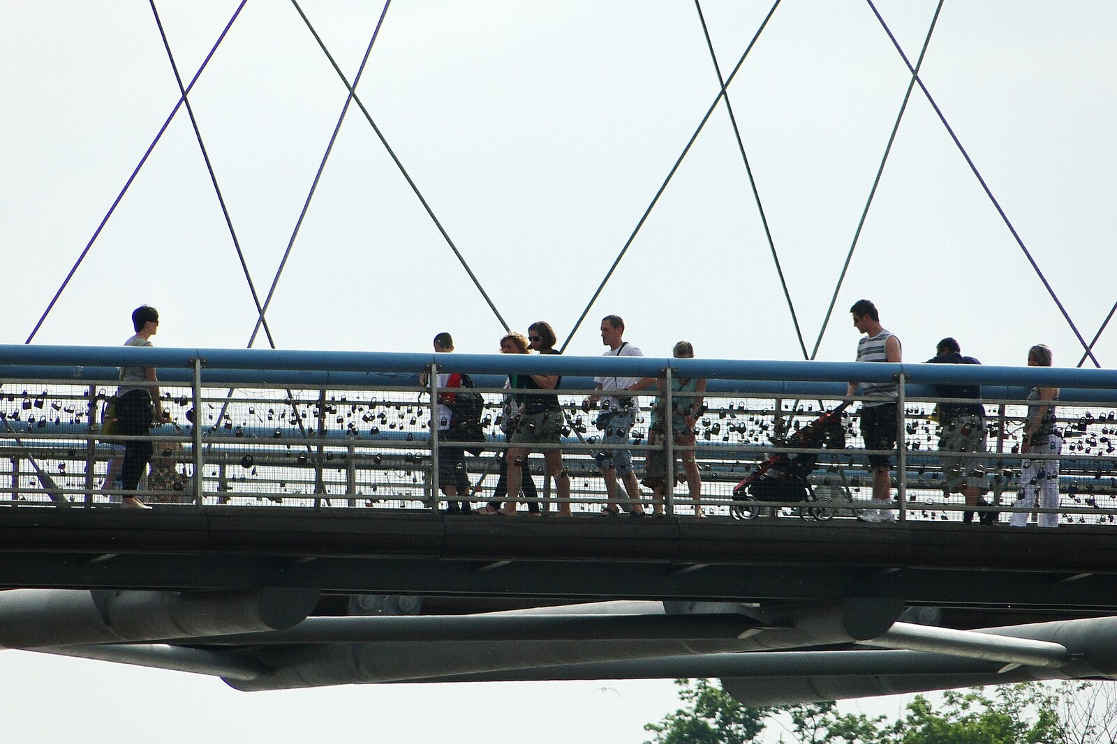 Puente peatonal moderno con esculturas suspendidas sobre el río Vístula.