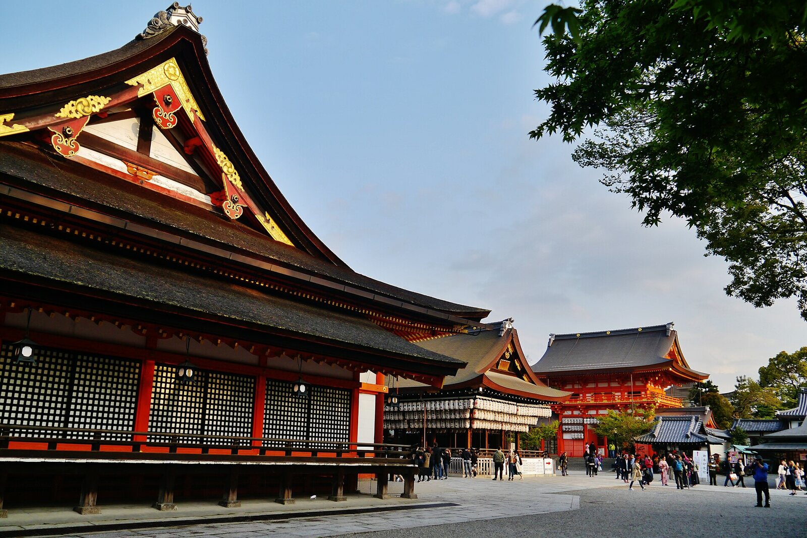 Evening courtyard of Yasaka Shrine with red gates and a stage.
