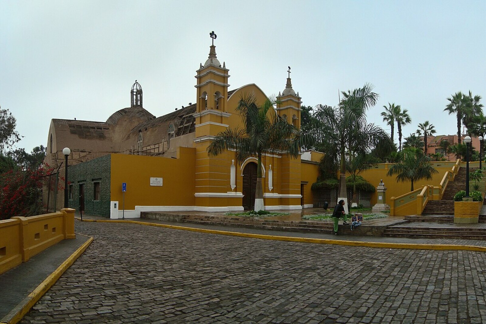 Neo-Gothic La Ermita Church with a yellow façade and towers, surrounded by greenery