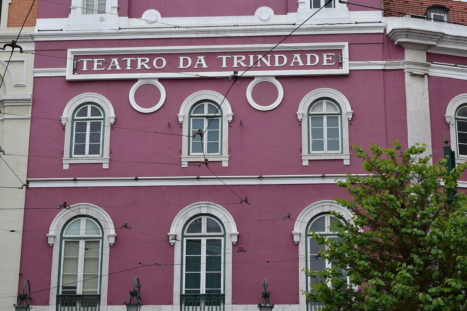 The pink facade of Teatro da Trindade on a small stone square.