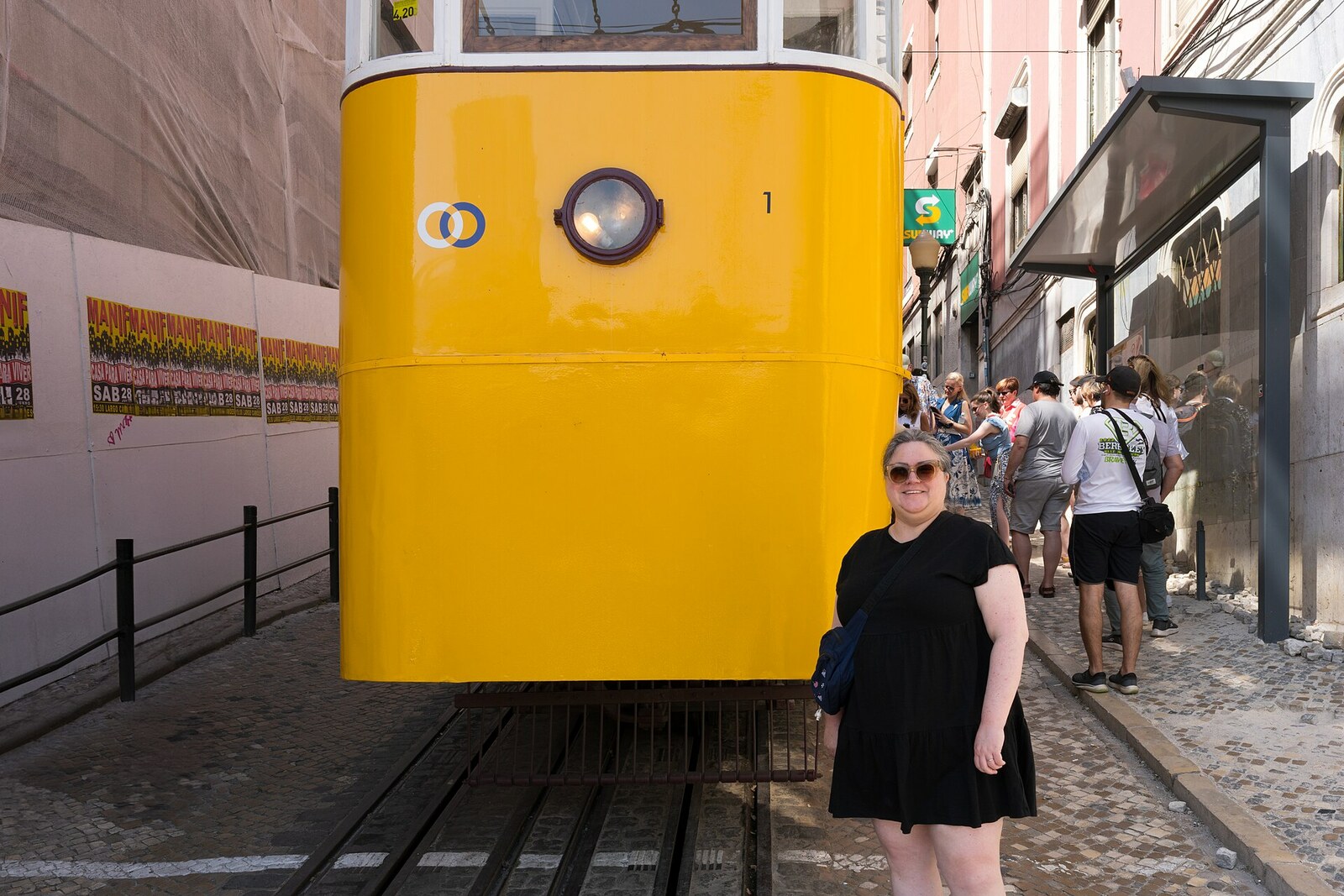 The yellow Bica Funicular travels along a steep street between historic houses.