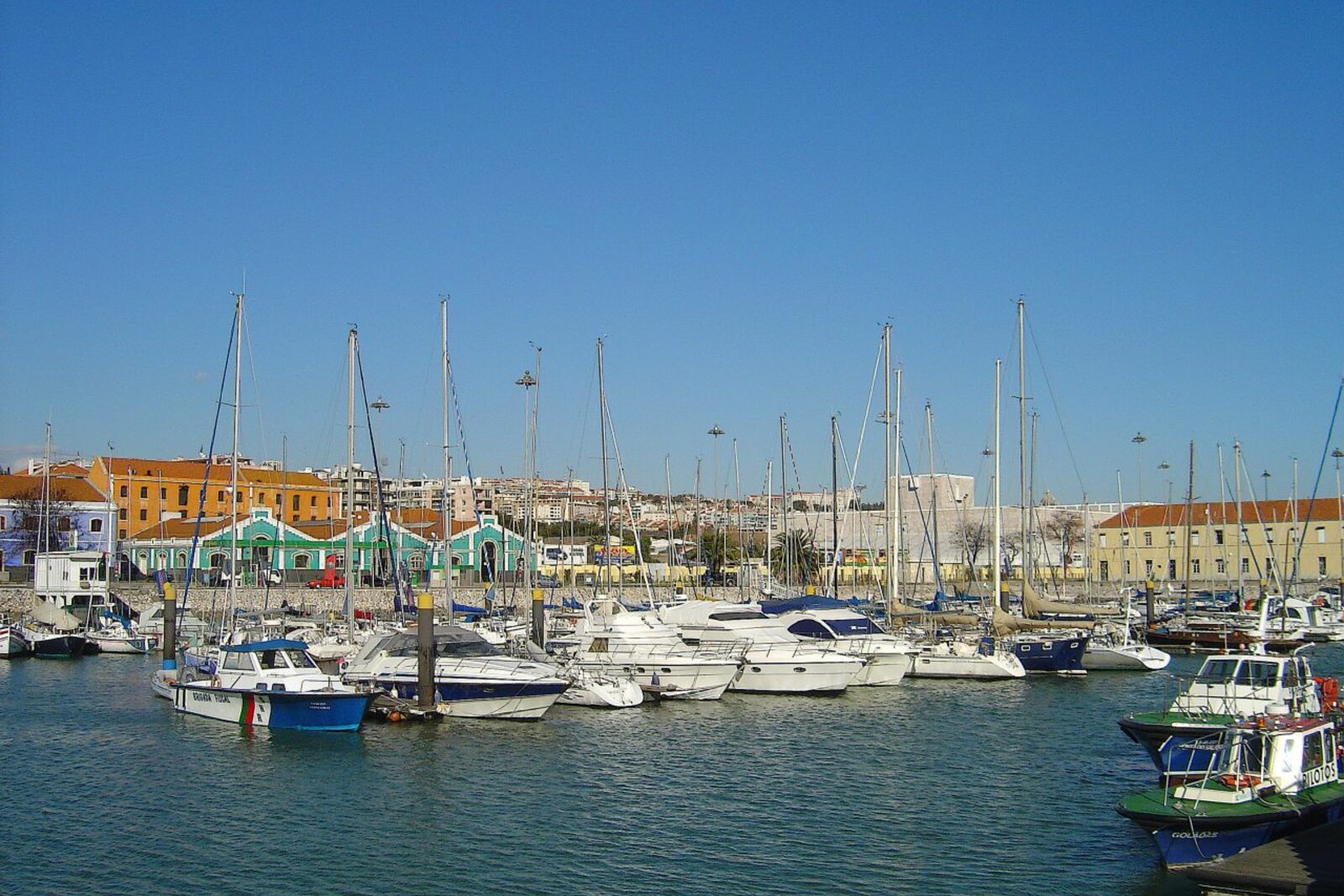 Bom Sucesso Dock marina with yachts, pontoons, and Belém Tower in the distance