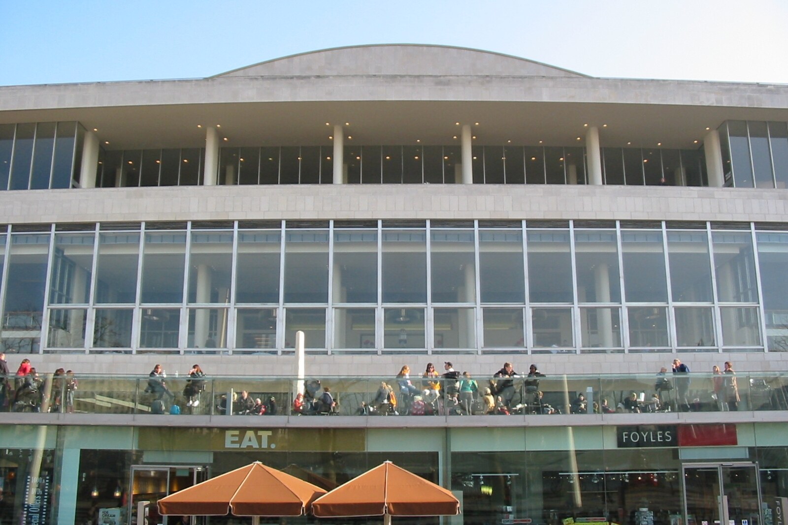 Concrete terraces of Royal Festival Hall with people relaxing and trees