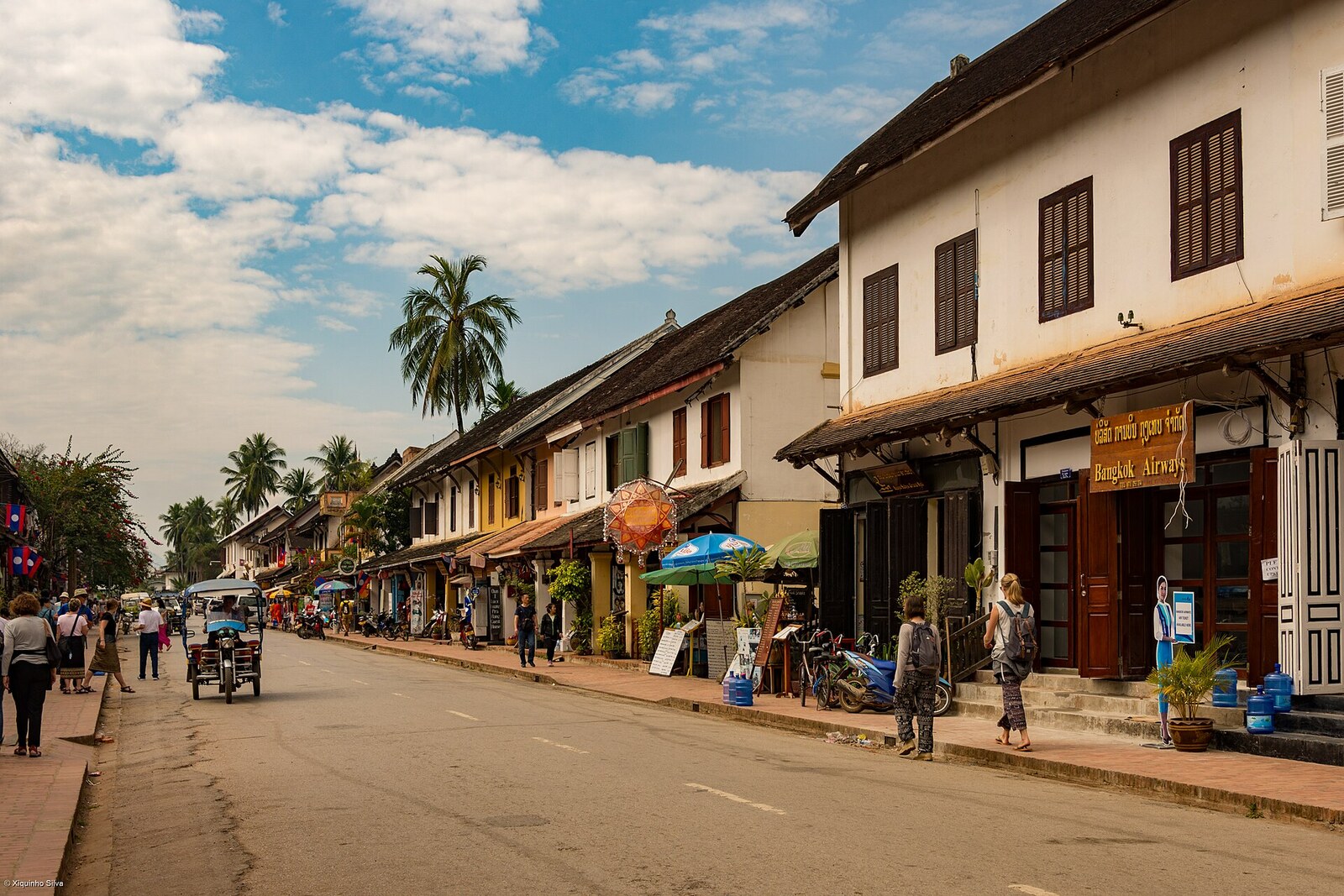 A historic street in Luang Prabang with wooden shutters and low roofs.