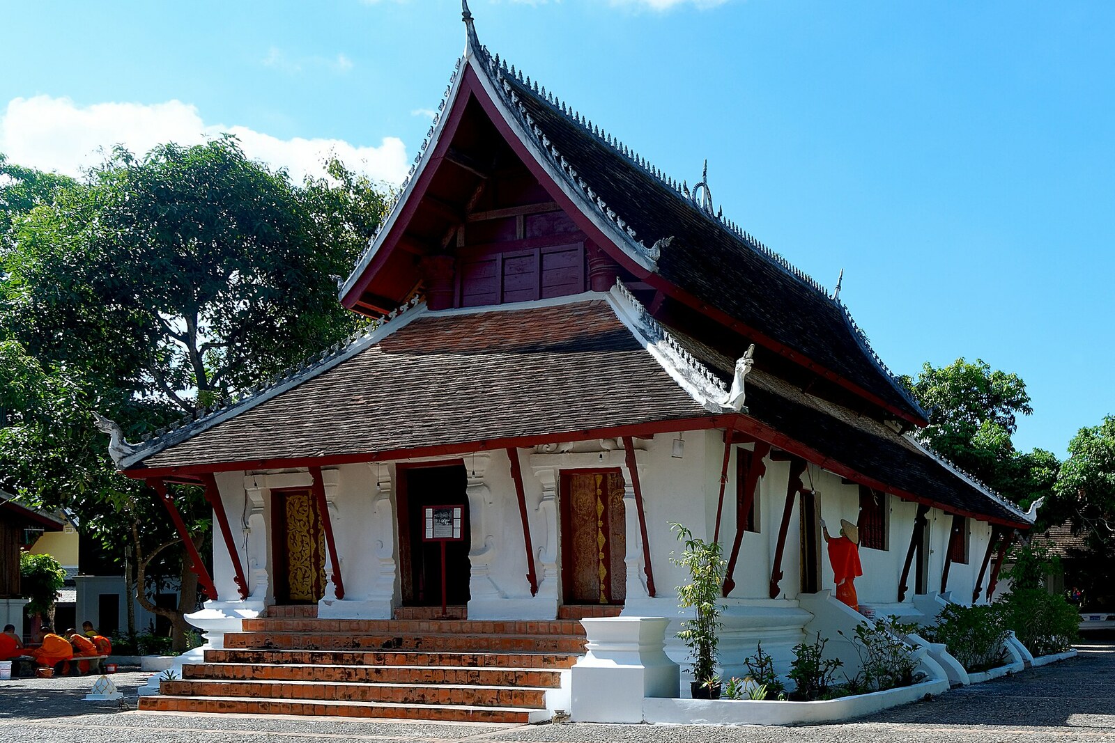 The small red-and-white main hall of Wat Pak Khan beneath a dark roof.
