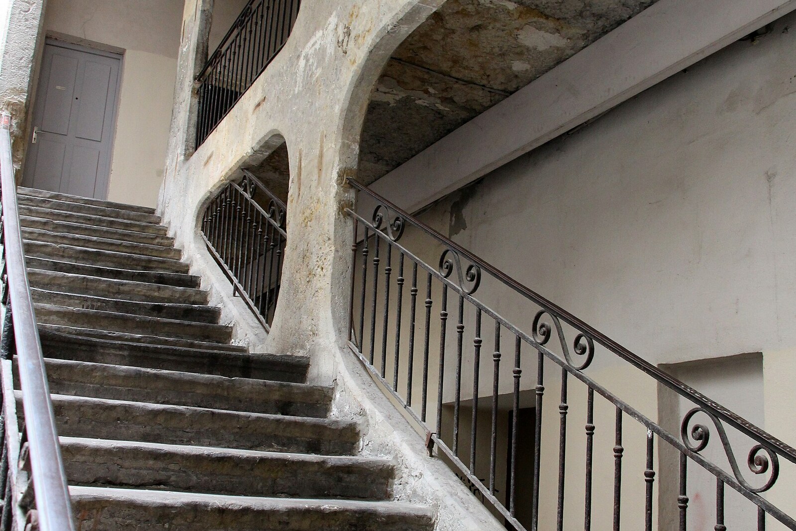 The tall open-air stone staircase of Cour des Voraces, leading to the upper floors of a building, with no people present.