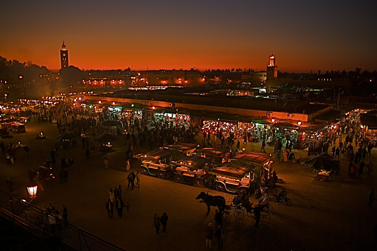Evening Jemaa el-Fnaa with the lights of the rows and the silhouette of Koutoubia Mosque.