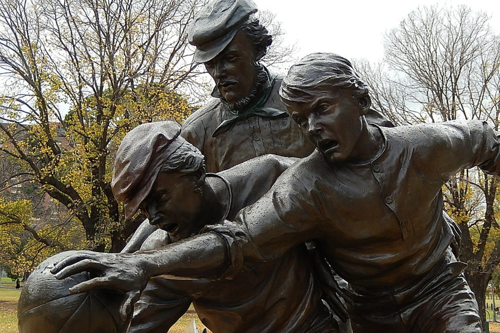 A bronze statue of Tom Wills holding a ball, on a pedestal in front of the stadium entrance