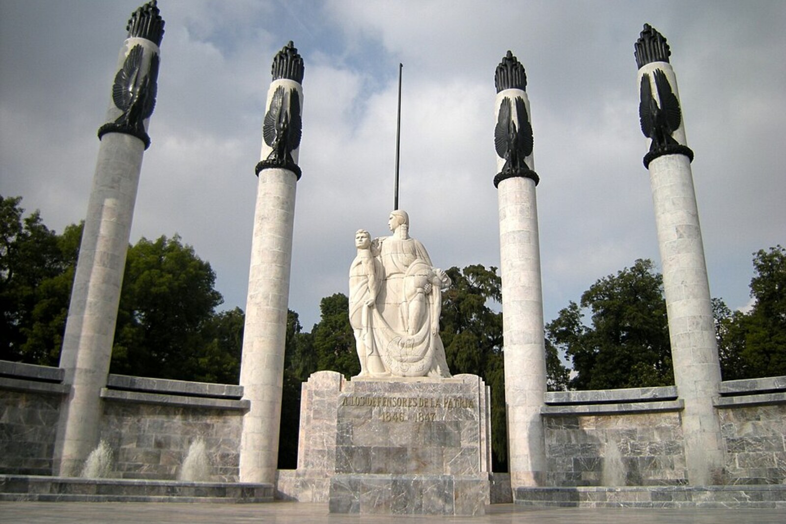 A semicircular marble monument with six columns and a central statue.