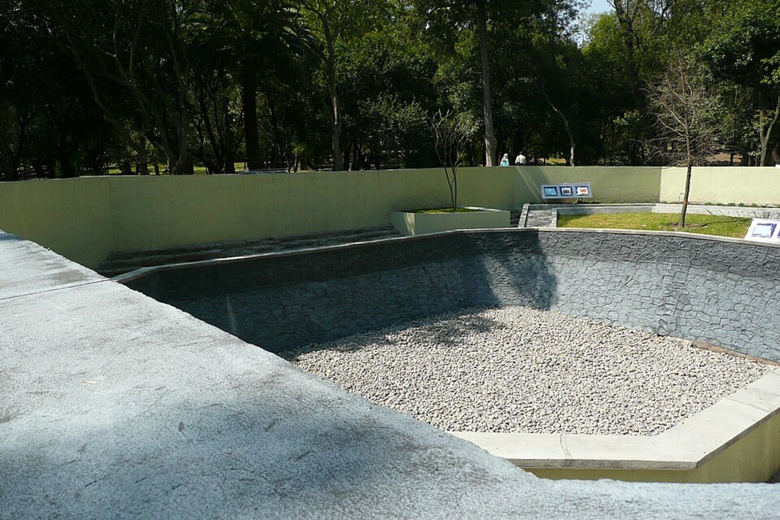 A stone pool with clear water and walls in the forest.