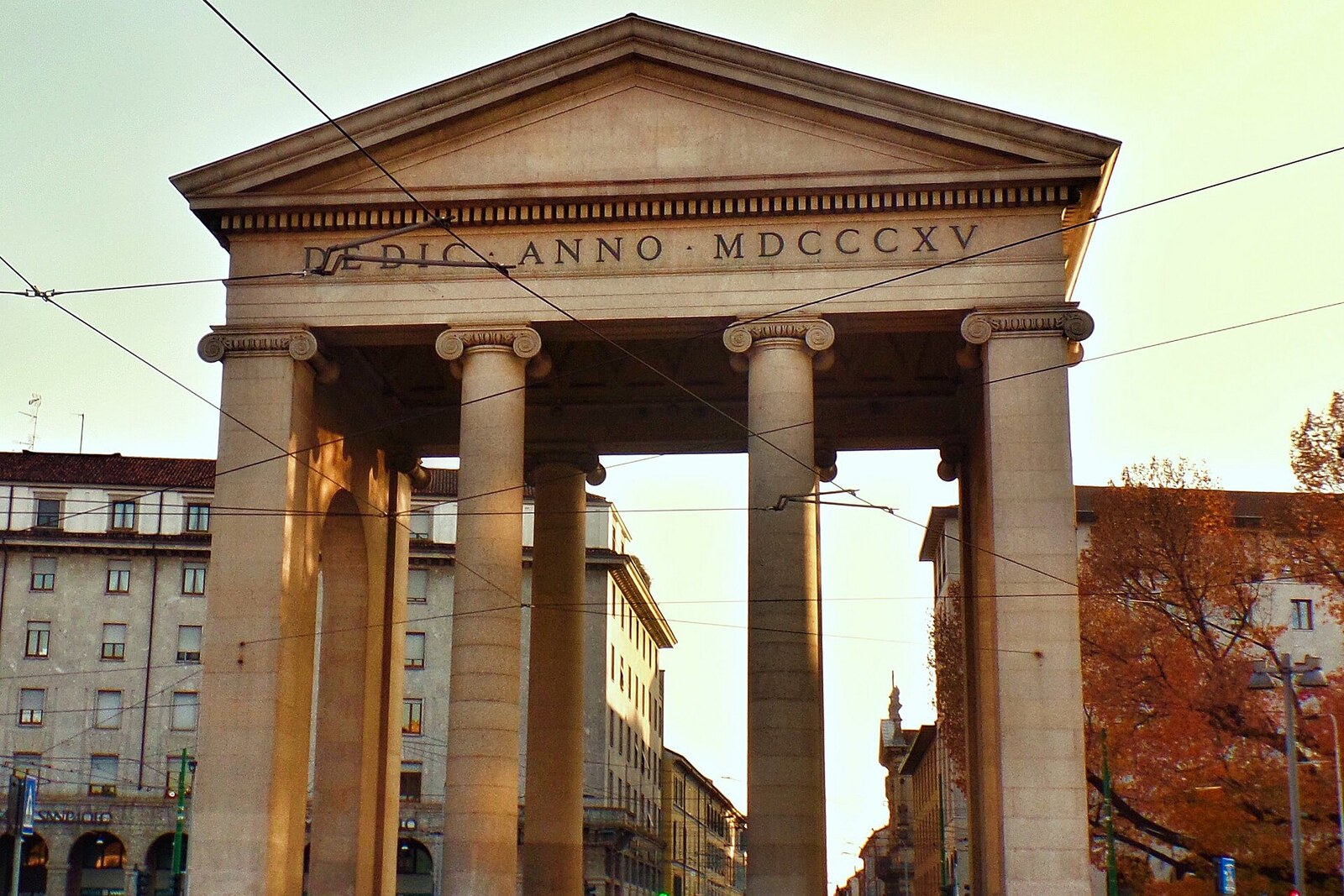 The neoclassical Porta Ticinese gates in Milan with trees in autumn foliage