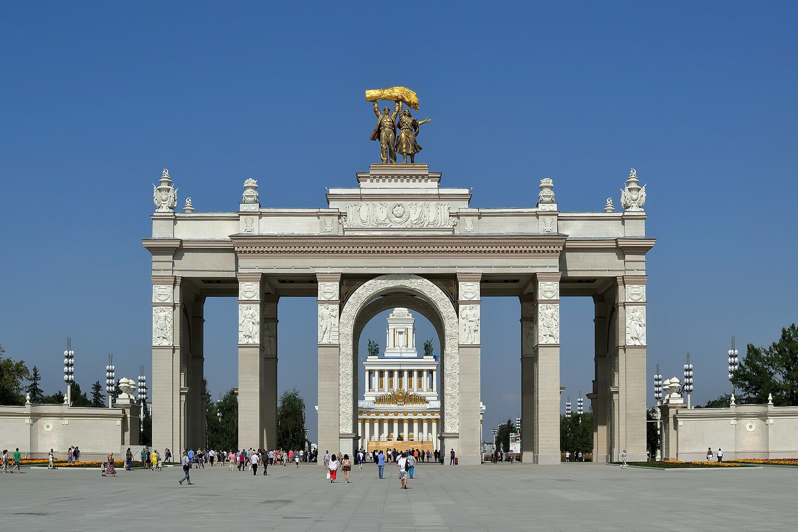 The VDNKh Main Entrance Arch, with the spire of the Central Pavilion visible through its central opening.