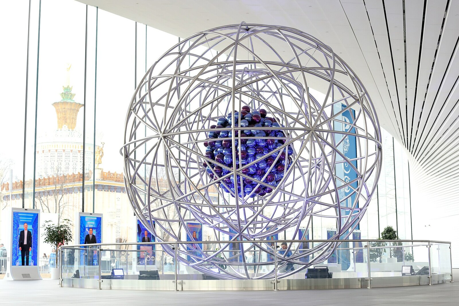 A large metal model of an atom in the bright interior of the ATOM Museum.