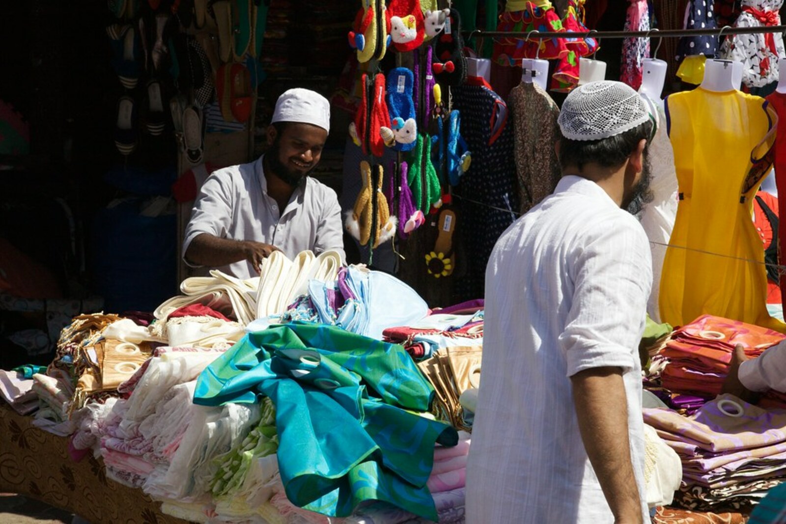 Puesto callejero con telas y ropa en un mercado de Bombay; vista contextual del entorno comercial junto a Bhuleshwar, no del interior del Mercado Mangaldas ni del Mercado Mulji Jetha.