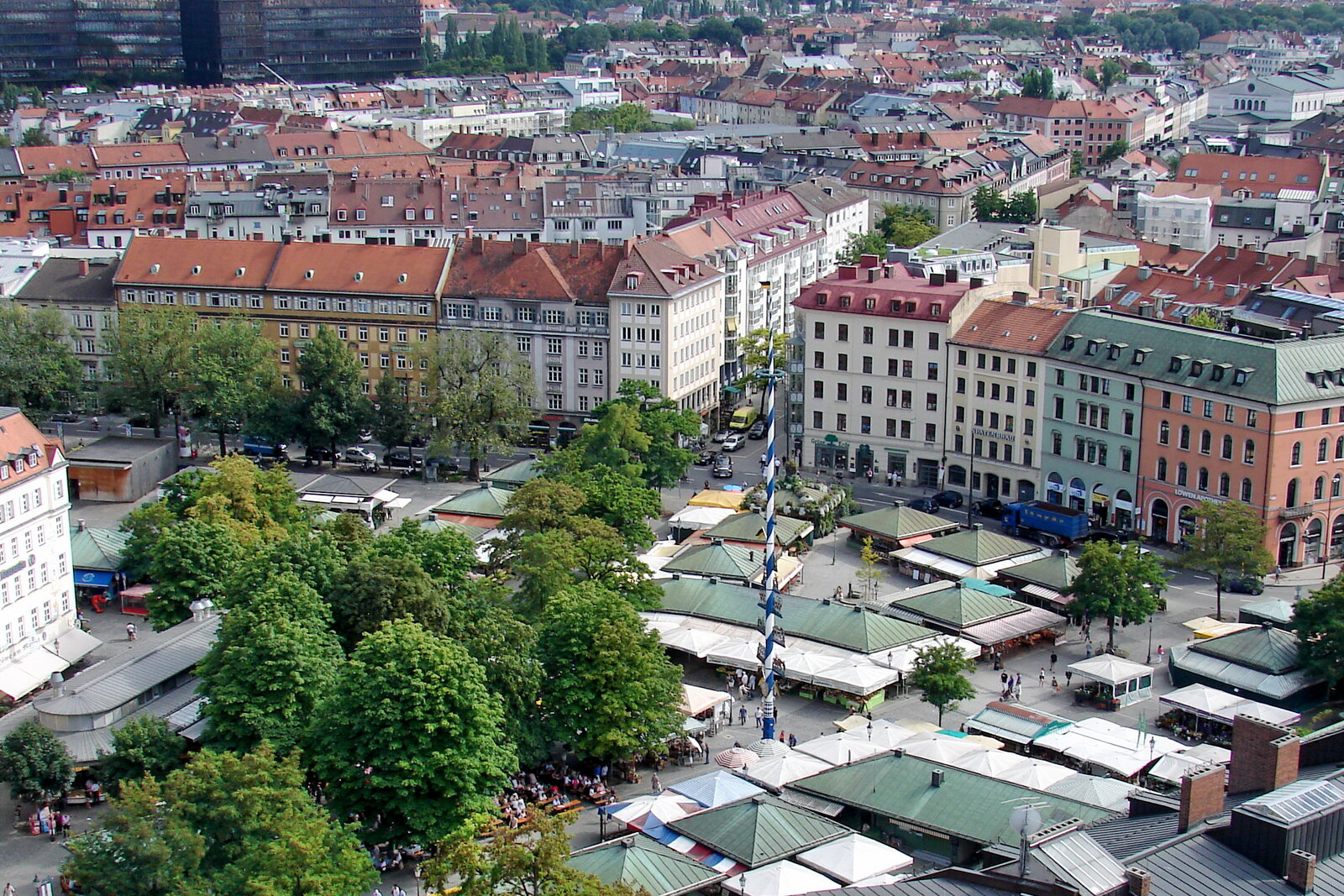 Viktualienmarkt with market stalls, trees, and city rooftops.