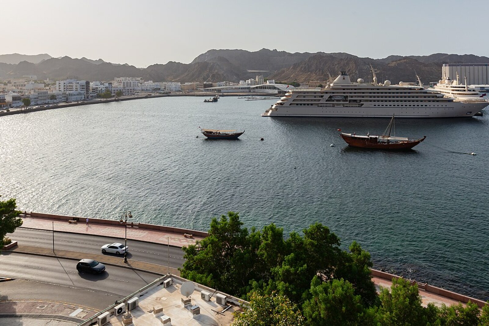 Mutrah port and the line of the corniche between the water, facades, and cliffs.