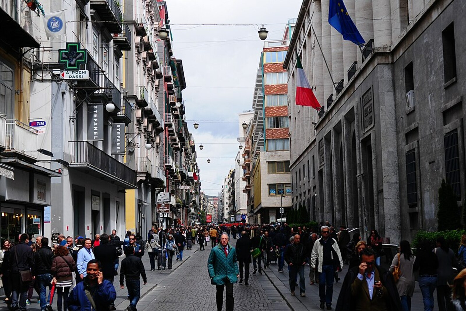 People walk along Via Toledo, surrounded by tall buildings and shops