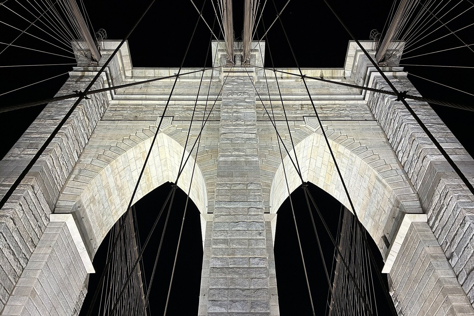 Tour en granit du pont de Brooklyn, avec ses câbles tendus, vue depuis la promenade