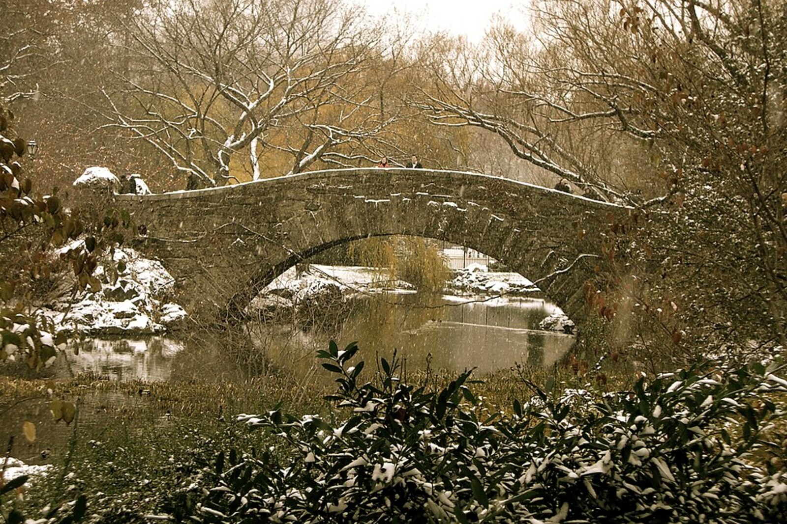 Gapstow Bridge, a stone arch bridge, over The Pond, with its reflection in the water and trees around it