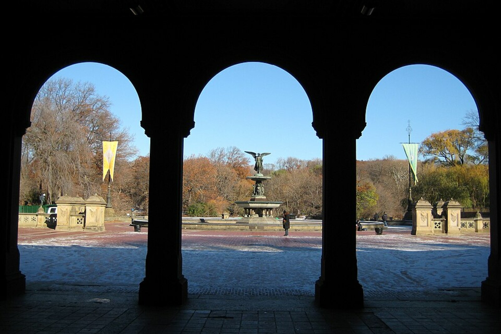 Bronze angel statue on Bethesda Fountain, surrounded by stone balustrades and arches