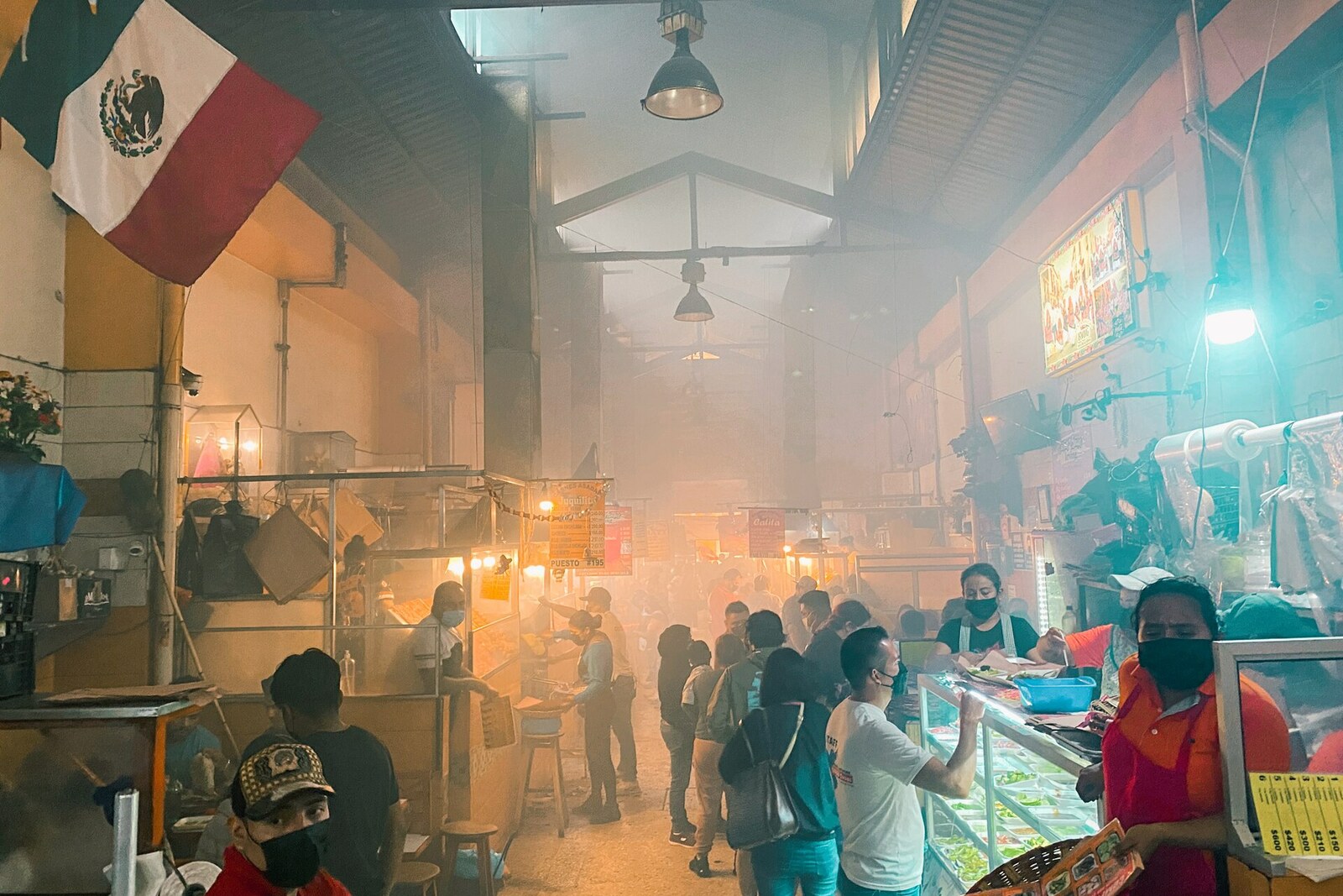 The Pasillo del Humo corridor in Mercado 20 de Noviembre: grills with roasting meat and smoke