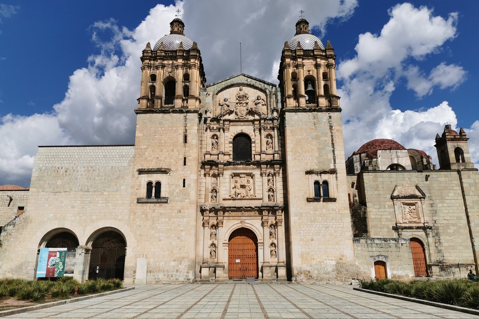 Façade of the Church of Santo Domingo de Guzmán in Oaxaca, with an open square in front of it.