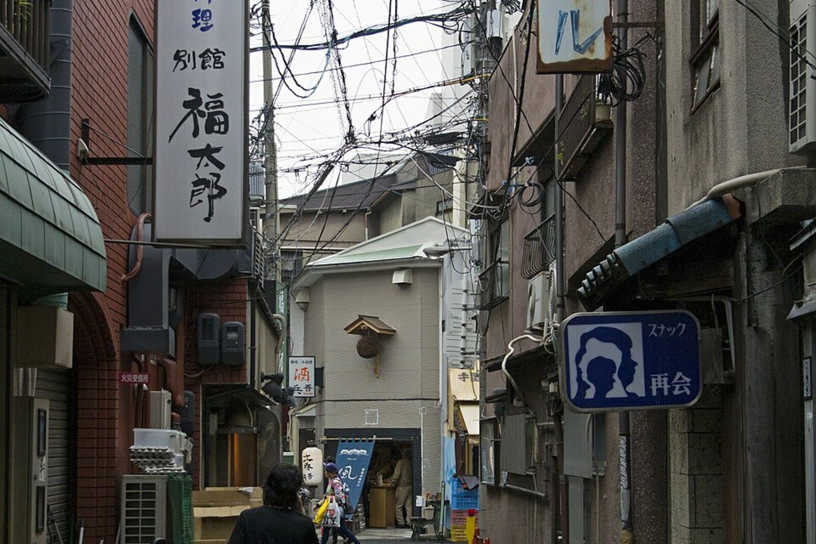 A narrow street in the Sennichimae/Namba area, with restaurant signs and passersby.