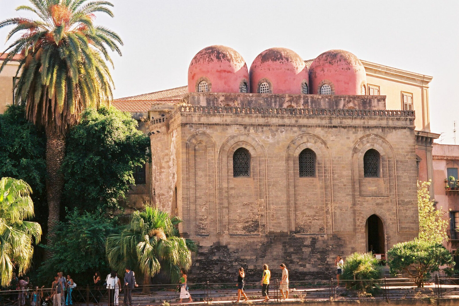 The stone façade of the Church of San Cataldo and three red domes.