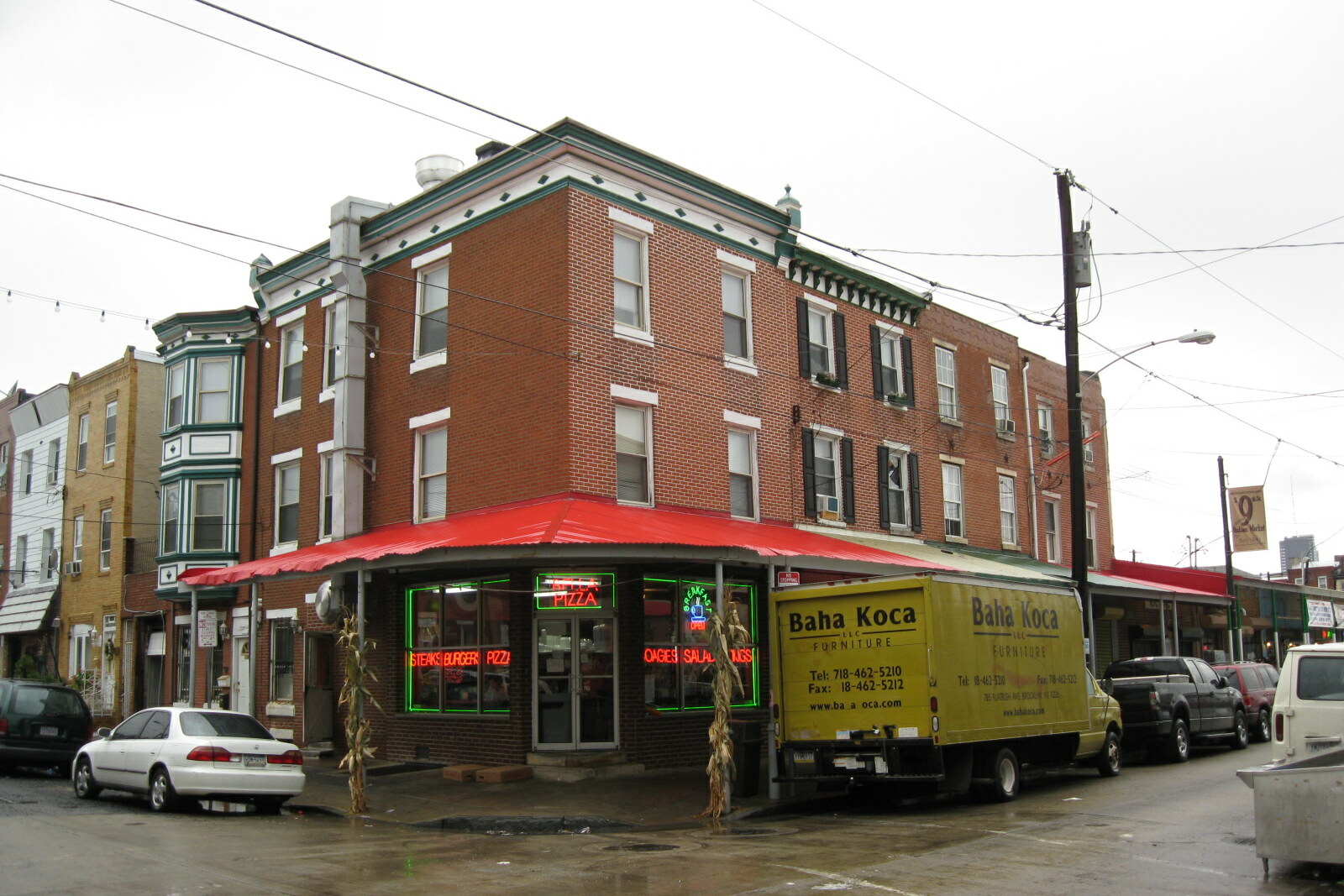Shops of the South 9th Street Italian Market, hung with awnings and merchandise, against a blue sky.