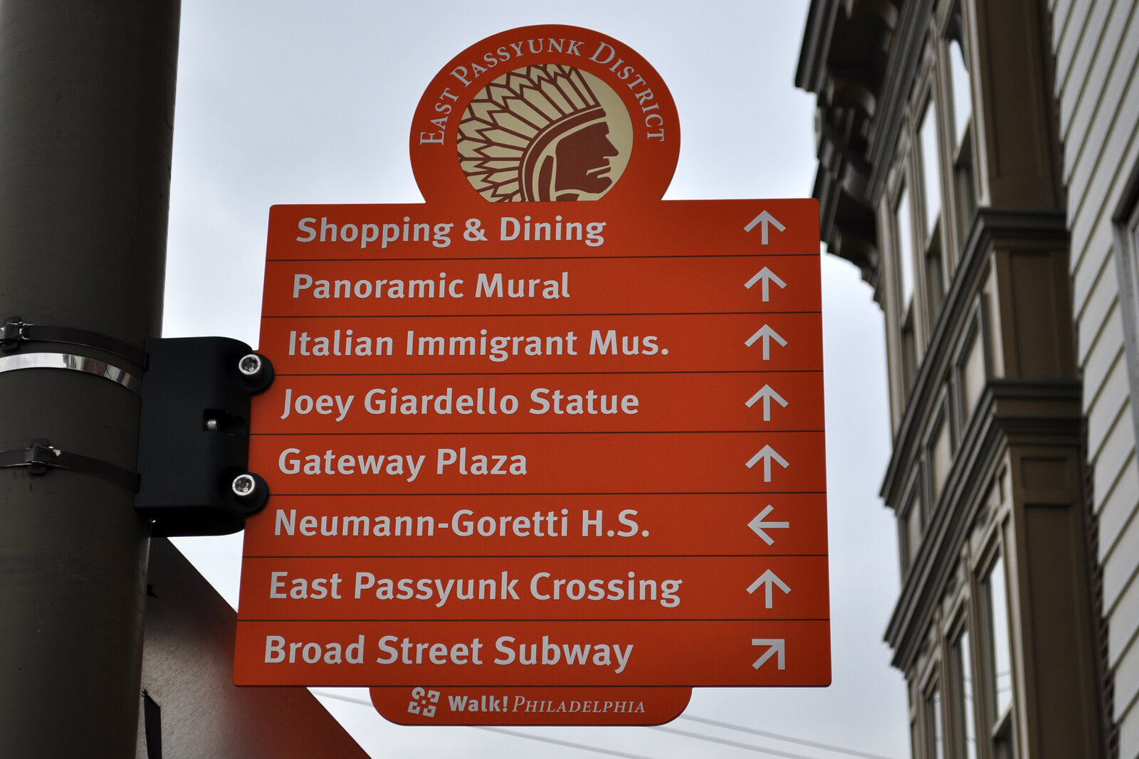An East Passyunk neighborhood wayfinding sign beside the Singing Fountain; a contextual neighborhood landmark, not a photo of the fountain itself.