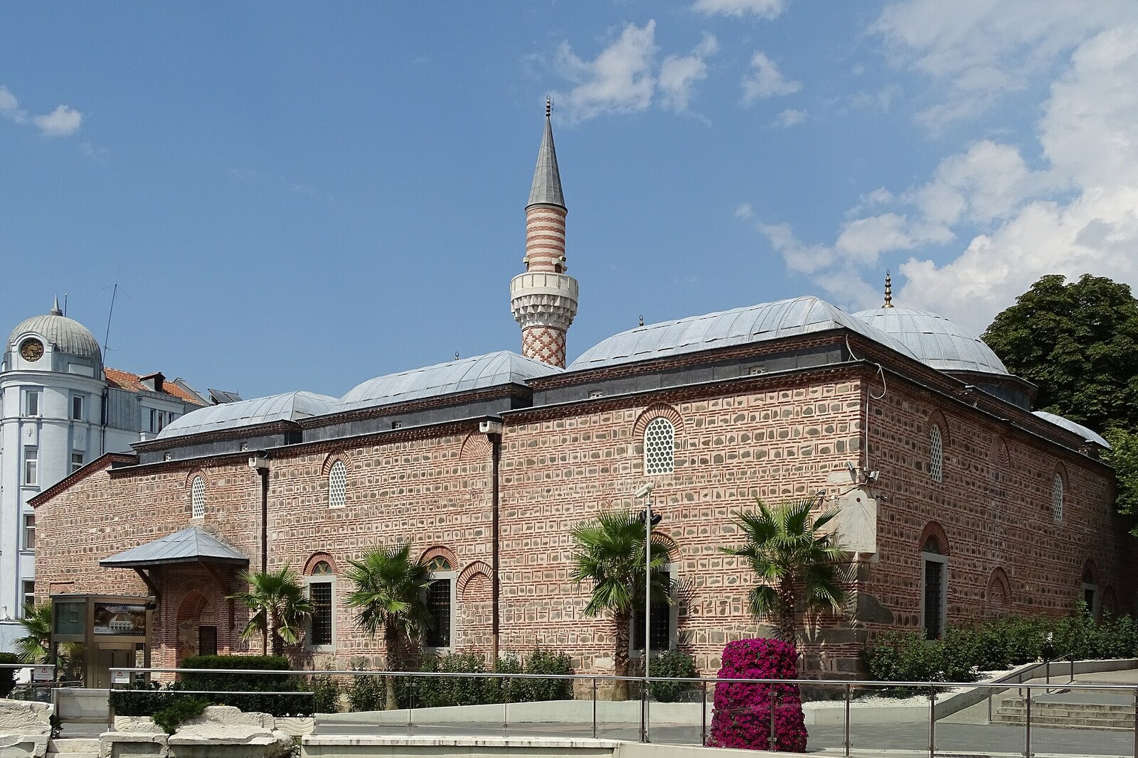 The broad brick-and-stone facade of Dzhumaya Mosque, with domes and a striped minaret