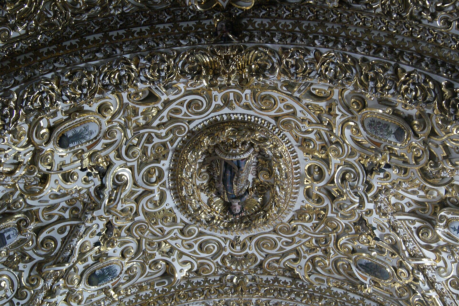 The gilded stucco vault of the Chapel of the Rosary, with windows and painted medallions.