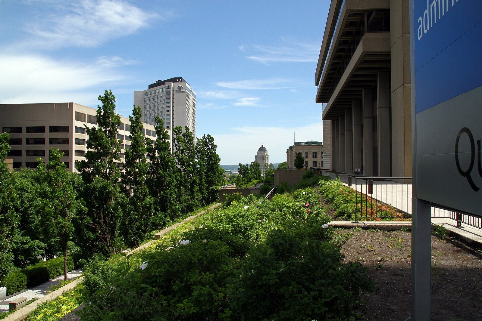 A pedestrian walkway with information panels and trees along Boulevard René-Lévesque.