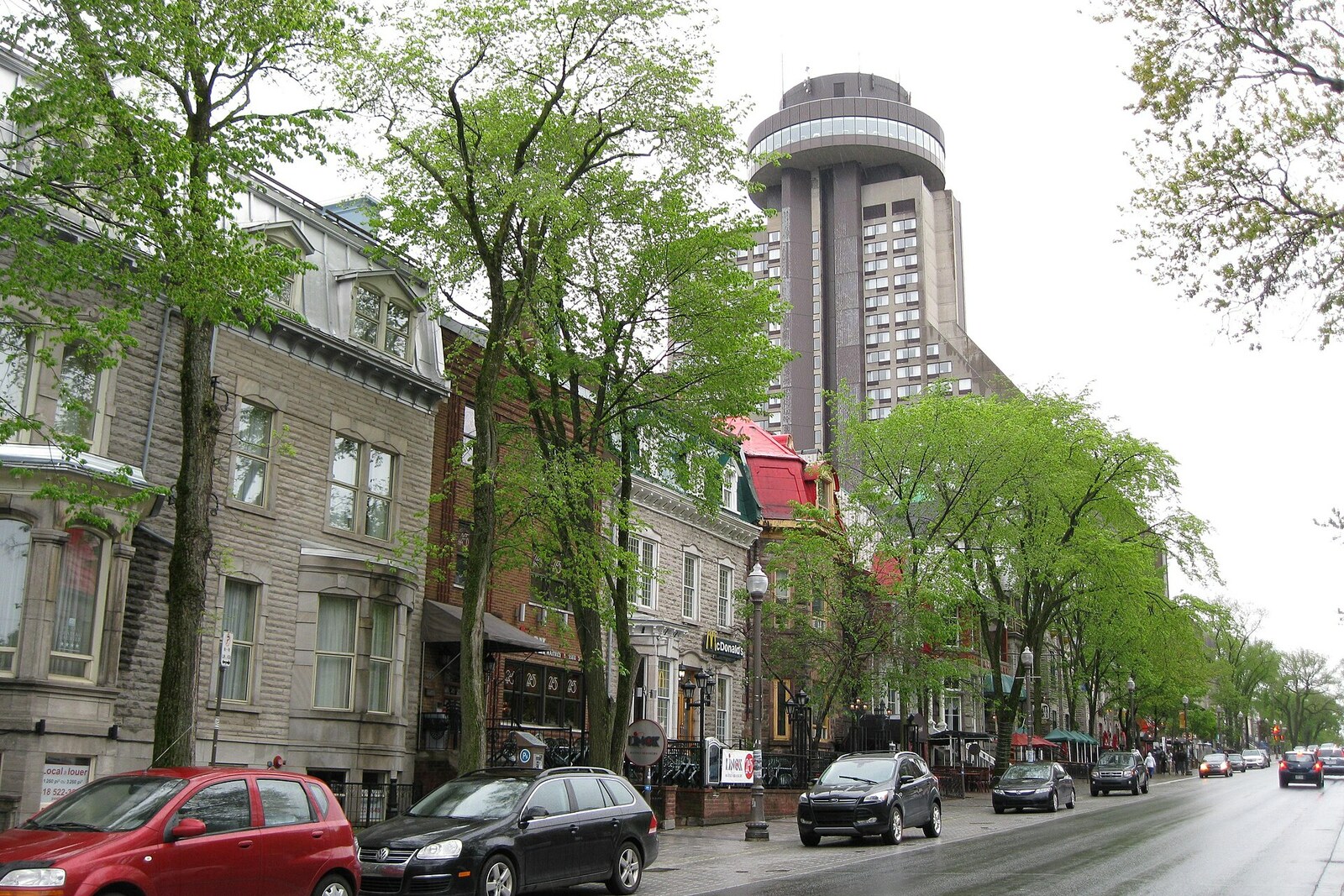 A shaded Grande Allée street with trees and historic houses.
