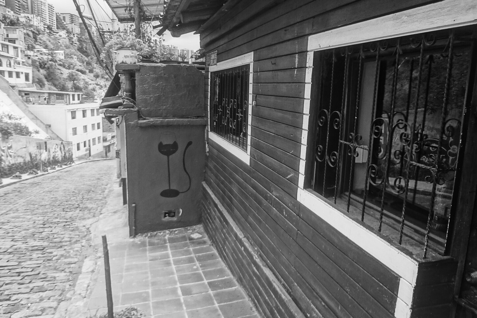 Black-and-white café façade on a steep cobblestone street in Guápulo.