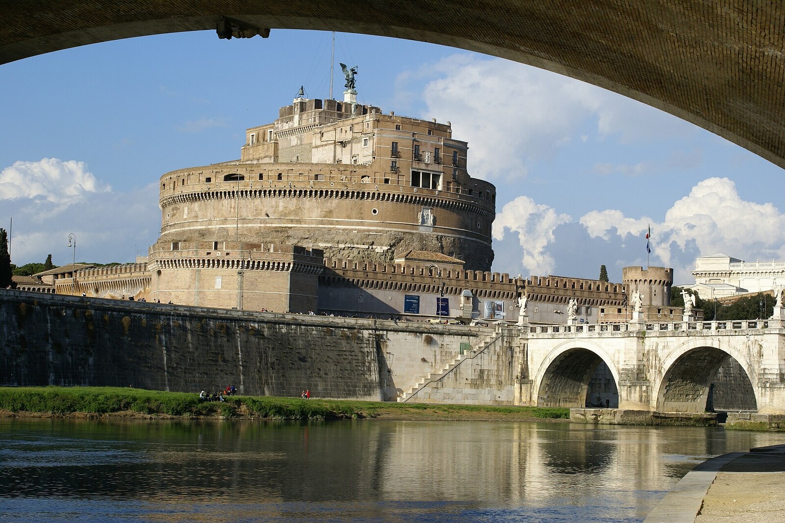 View of Castel Sant'Angelo from the opposite bank of the Tiber, emphasizing the fortress's circular shape and the angel statue.
